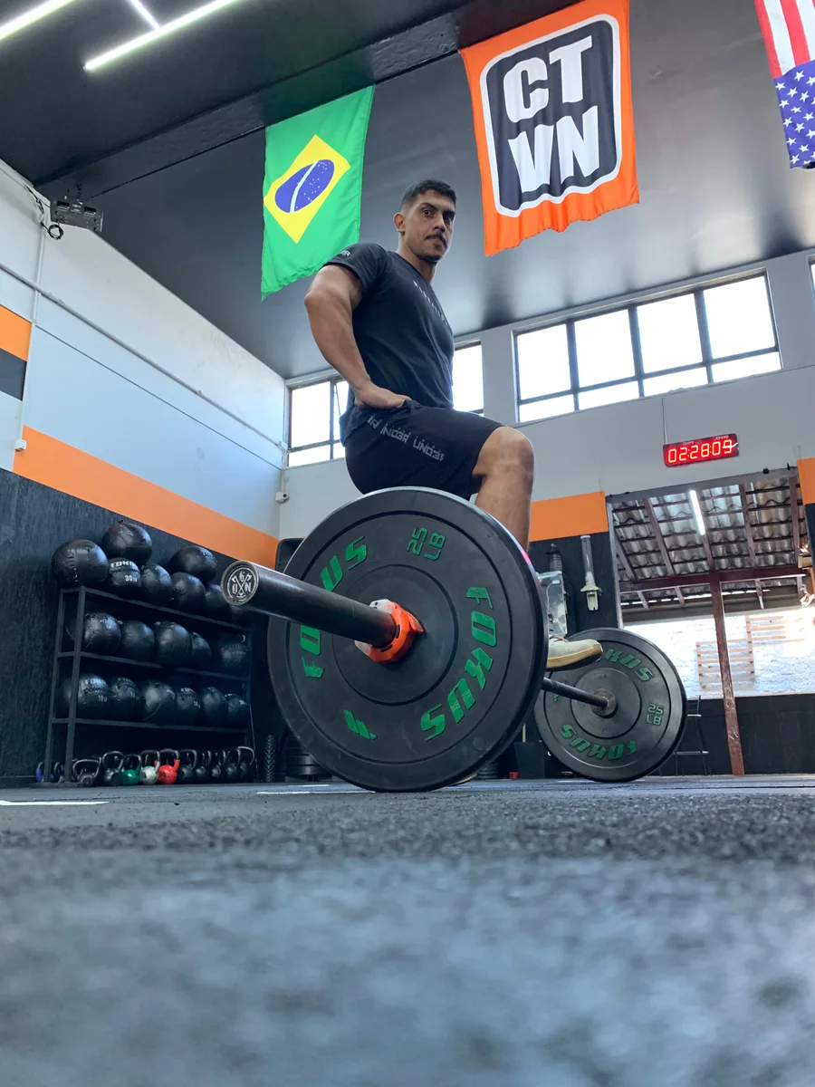 Atleta com a barra no chão e o LIFT laranja preso junto às anilhas